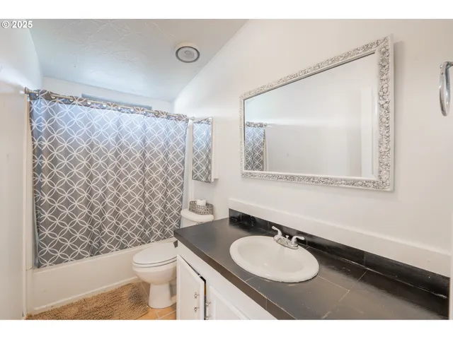 a bathroom with a granite countertop sink mirror vanity and toilet
