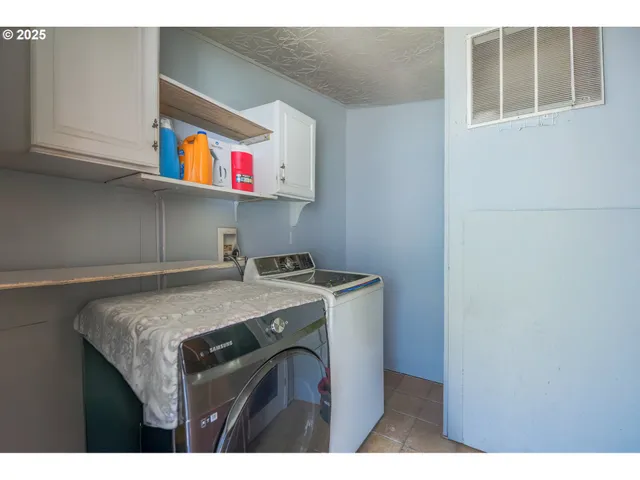 a utility room with stainless steel appliances granite countertop a sink and a cabinets