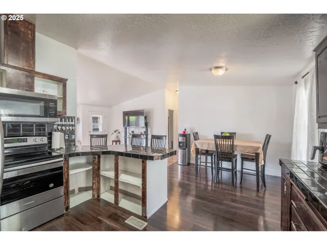 a kitchen with stainless steel appliances granite countertop a stove top oven a dining table and chairs with wooden floor