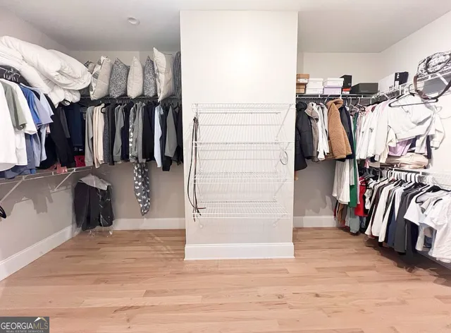 an empty room with wooden floor closet and windows