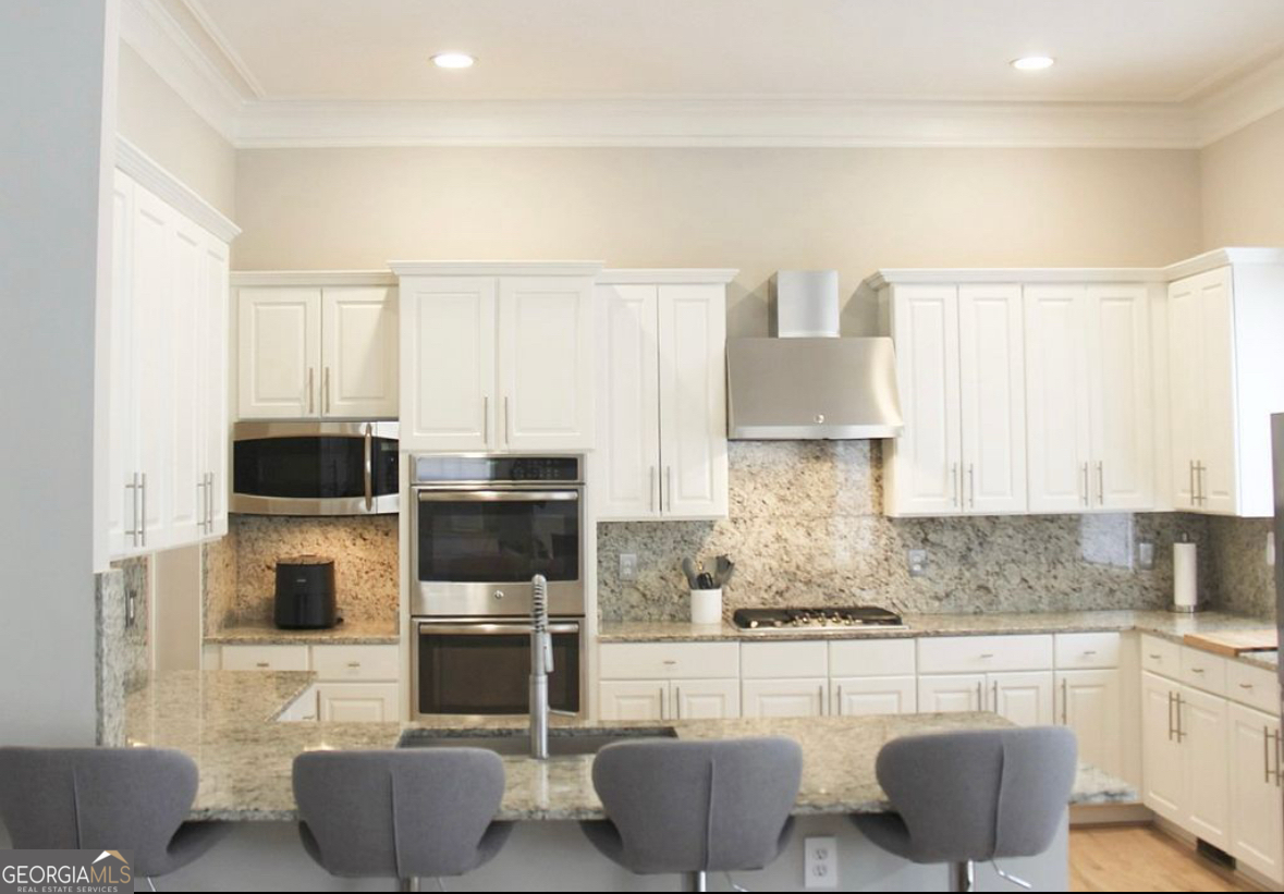 996 Pitts Road, Unit D Sandy Springs, GA 30350 - Photo 6 of 39 a kitchen with stainless steel appliances a stove a sink and white cabinets