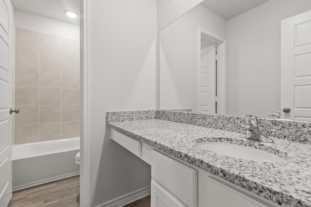 1607 Romans Road Ennis, TX 75119 - Photo 8 of 15 a bathroom with a granite countertop sink and a bathtub