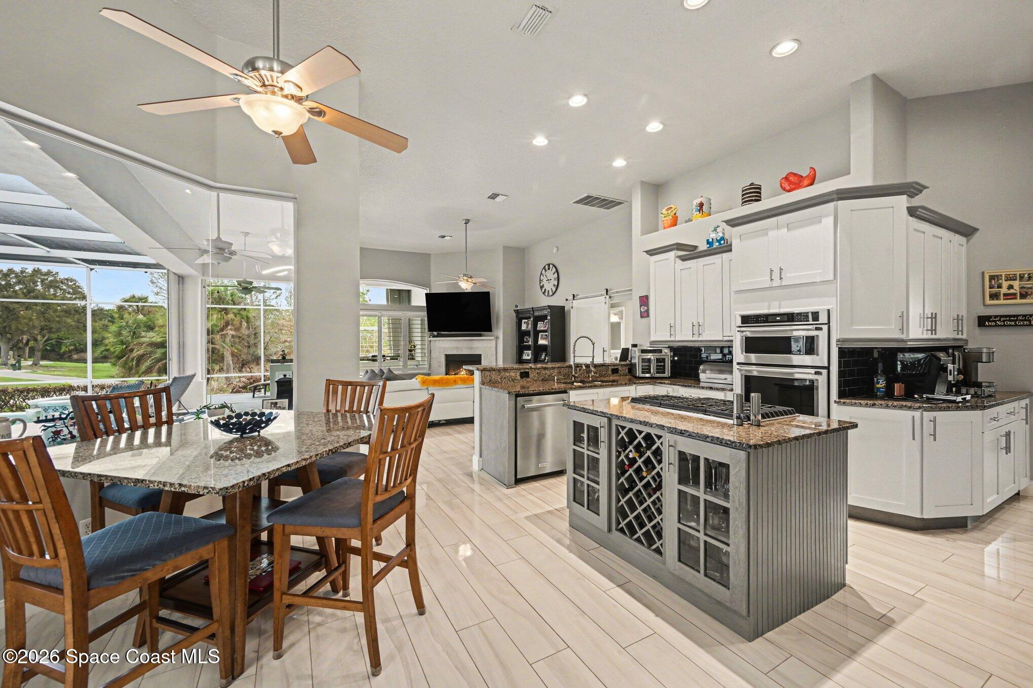 4317 Collingtree Drive Rockledge, FL 32955 - Photo 14 of 64 a kitchen with stainless steel appliances a stove a sink dishwasher a dining table and chairs with wooden floor