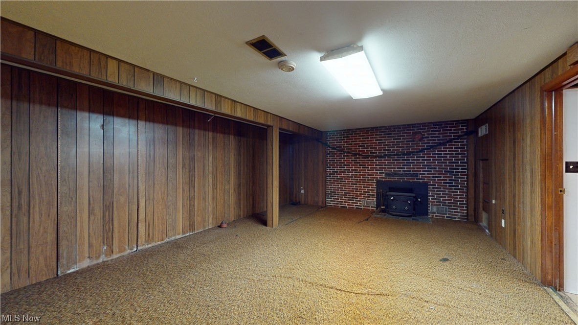 9600 Mennonite Road Wadsworth, OH 44281 - Photo 35 of 35 Basement featuring a wood stove, wood walls, and light colored carpet