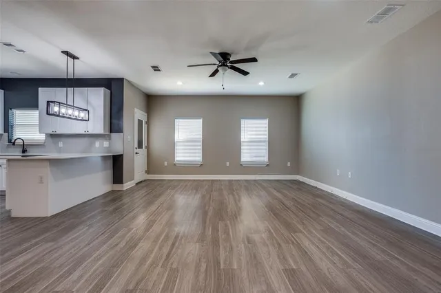 a view of an empty room with window and wooden floor