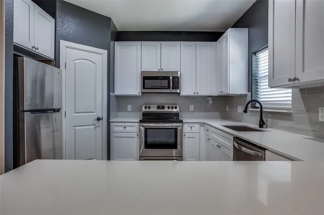 a kitchen with white cabinets and stainless steel appliances