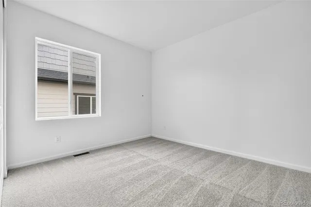 an empty room with wooden floor chandelier and windows