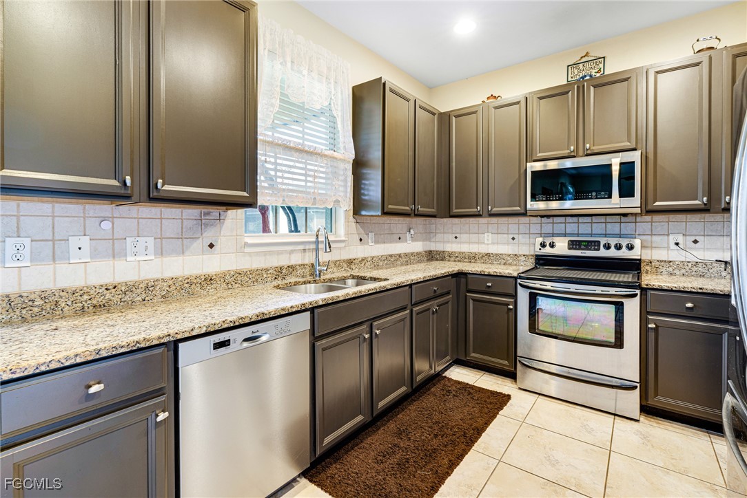 8657 Sumner Avenue Fort Myers, FL 33908 - Photo 9 of 29 a kitchen with stainless steel appliances granite countertop a sink stove and microwave