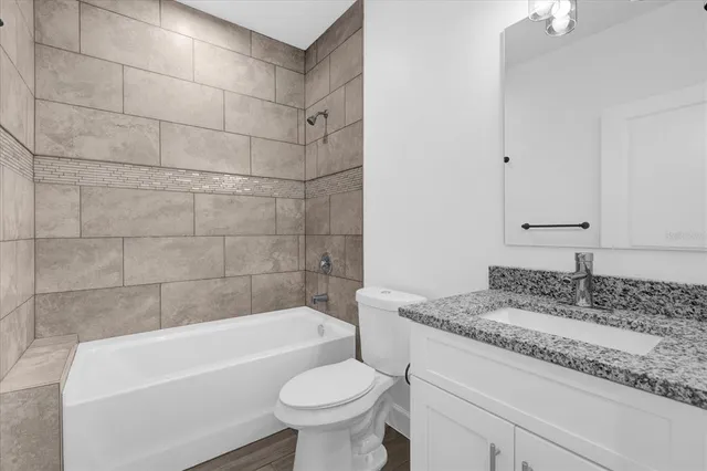 a bathroom with a granite countertop bathtub shower sink and toilet