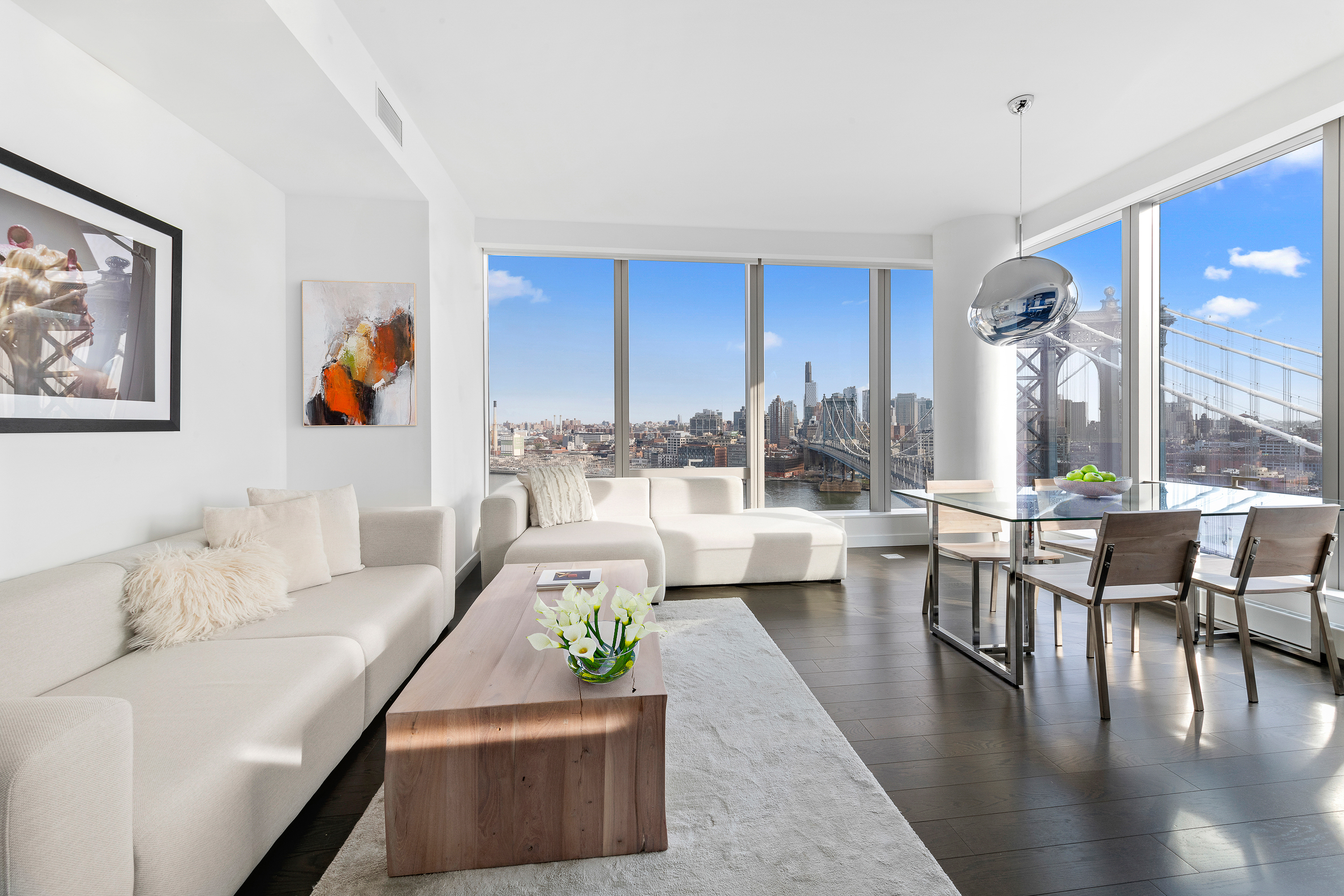 252 South Street, Unit 25D Manhattan, NY 10002 - Photo 4 of 36 a living room with couches a coffee table and kitchen view with wooden floor