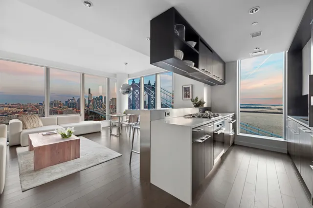 a living room with couches a coffee table and kitchen view with wooden floor