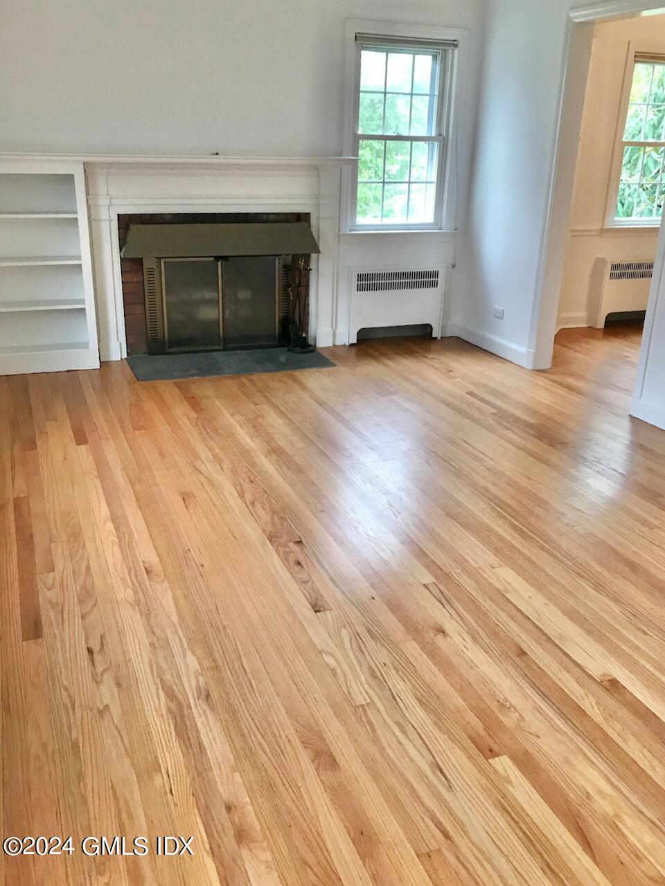7 River Lane Cos Cob, CT 06807 - Photo 7 of 30 an empty room with wooden floor fireplace and windows