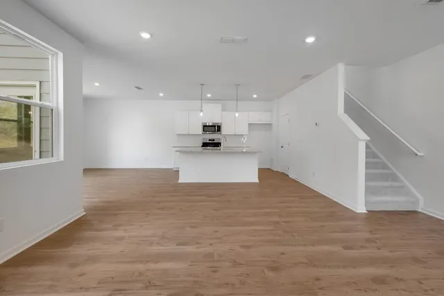 a view of a kitchen with kitchen island a sink wooden floor and a refrigerator