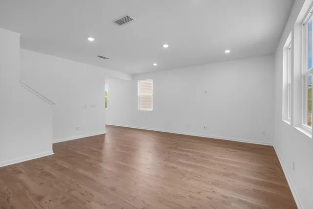 an empty room with wooden floor and windows