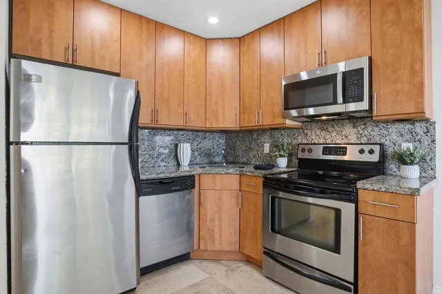 a kitchen with stainless steel appliances wooden cabinets and a stove top oven