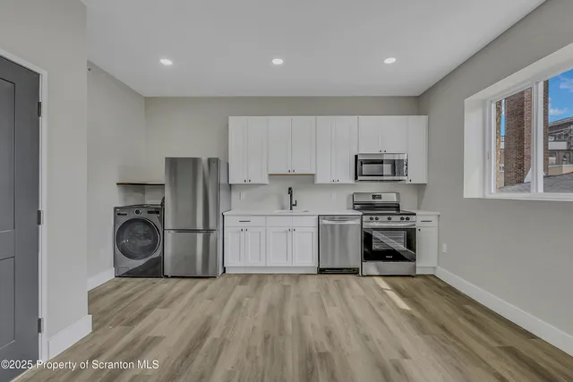 a kitchen with granite countertop white cabinets and stainless steel appliances