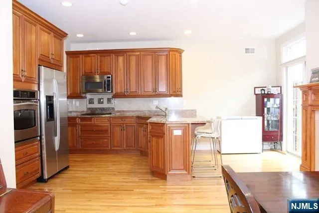 a kitchen with stainless steel appliances a stove top oven a sink refrigerator and cabinets