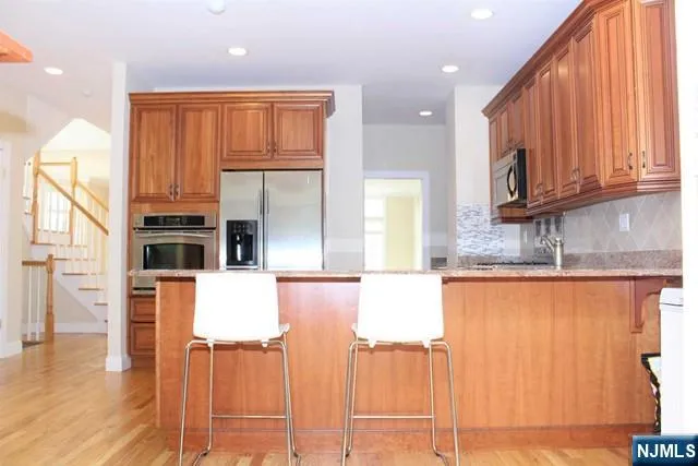 a kitchen with stainless steel appliances granite countertop a refrigerator a stove top oven with wooden floor and cabinets