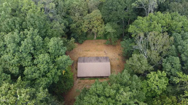 an aerial view of a house with a yard and trees all around