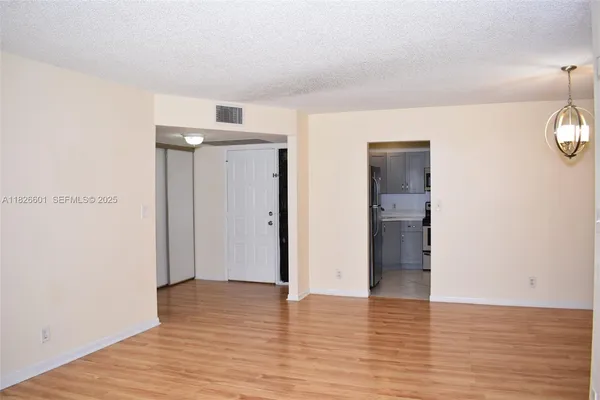 a view of an empty room with wooden floor and closet
