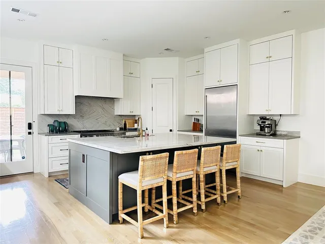 a kitchen with stainless steel appliances granite countertop a white table and chairs in it
