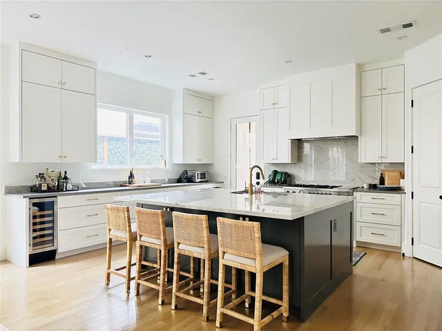 a kitchen with stainless steel appliances granite countertop a table chairs stove and white cabinets