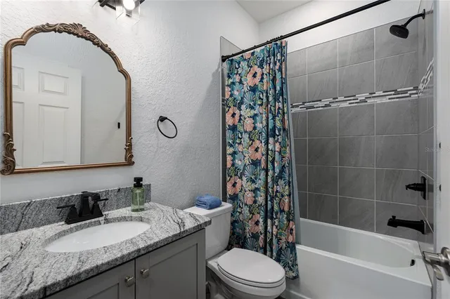 a bathroom with a granite countertop sink a toilet and shower
