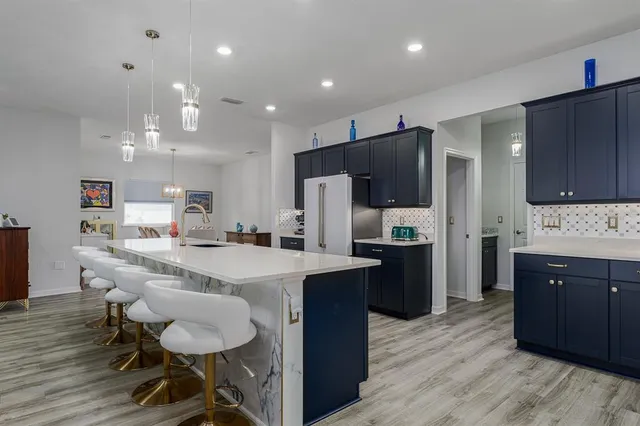 a kitchen with stainless steel appliances kitchen island granite countertop a sink refrigerator and cabinets