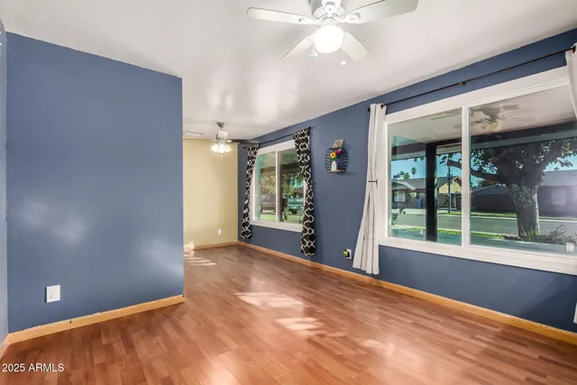 a view of empty room with wooden floor and fan