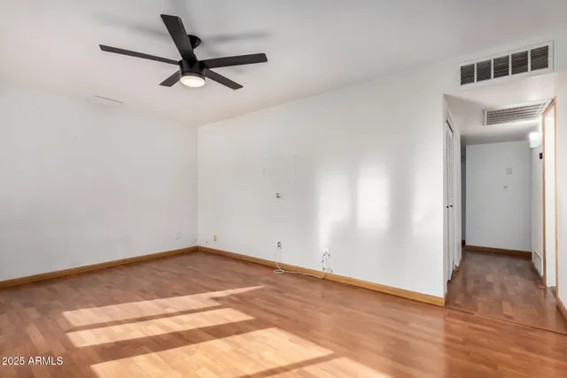 a view of a big room with wooden floor and windows