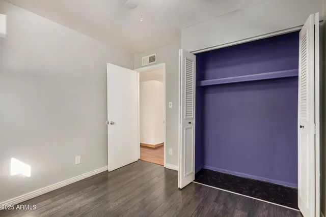 a view of an empty room with wooden floor & door
