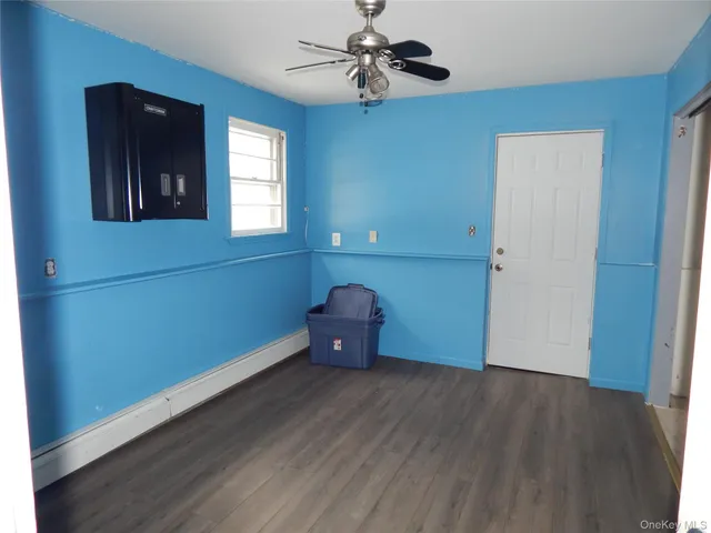 an empty room with wooden floor chandelier fan and windows