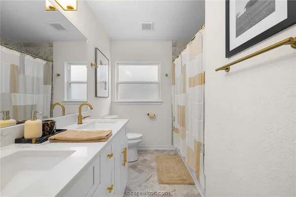 a bathroom with a granite countertop sink a toilet and a mirror