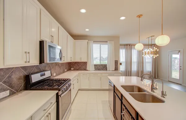 a large kitchen with kitchen island a large counter space a sink stainless steel appliances and cabinets