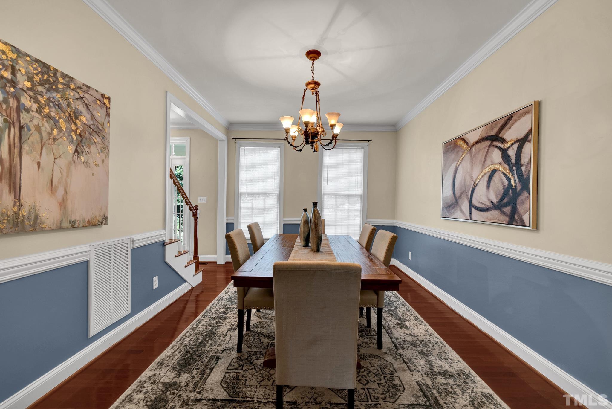 1012 Tyrrell Road Raleigh, NC 27609 - Photo 3 of 24 a dining room with wooden floor a chandelier a wooden table and chairs