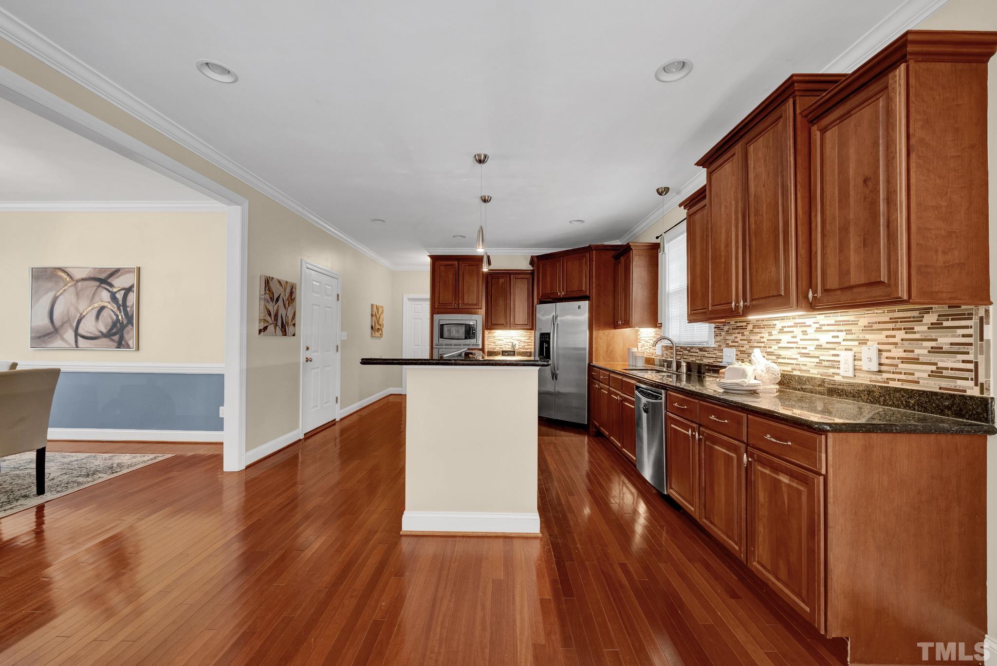 1012 Tyrrell Road Raleigh, NC 27609 - Photo 5 of 24 a kitchen with stainless steel appliances granite countertop wooden floors and wooden cabinets