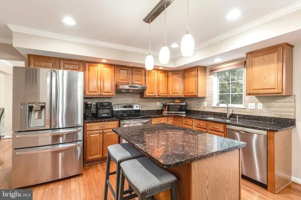 a kitchen with stainless steel appliances granite countertop a refrigerator a sink dishwasher a stove and white countertops with wooden floor