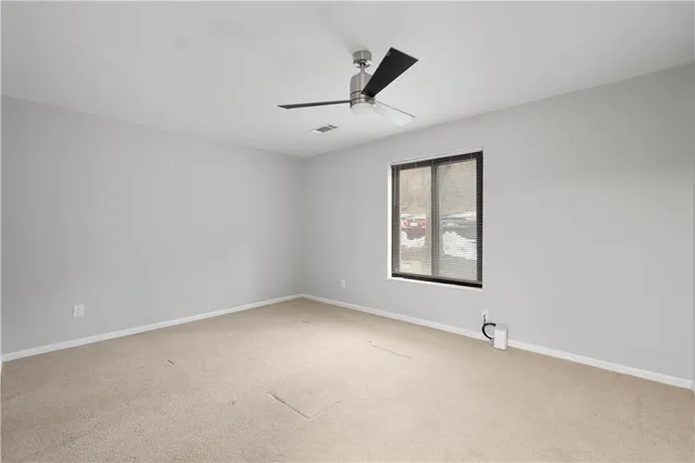 an empty room with a window and ceiling fan