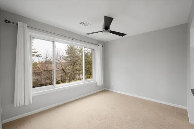 a view of an empty room with a window and kitchen view