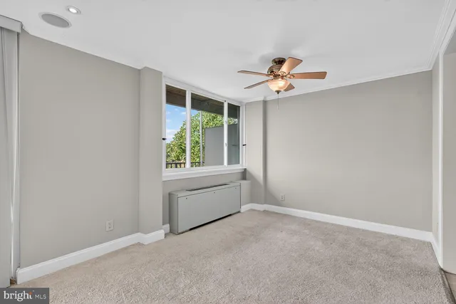 an empty room with windows and fan