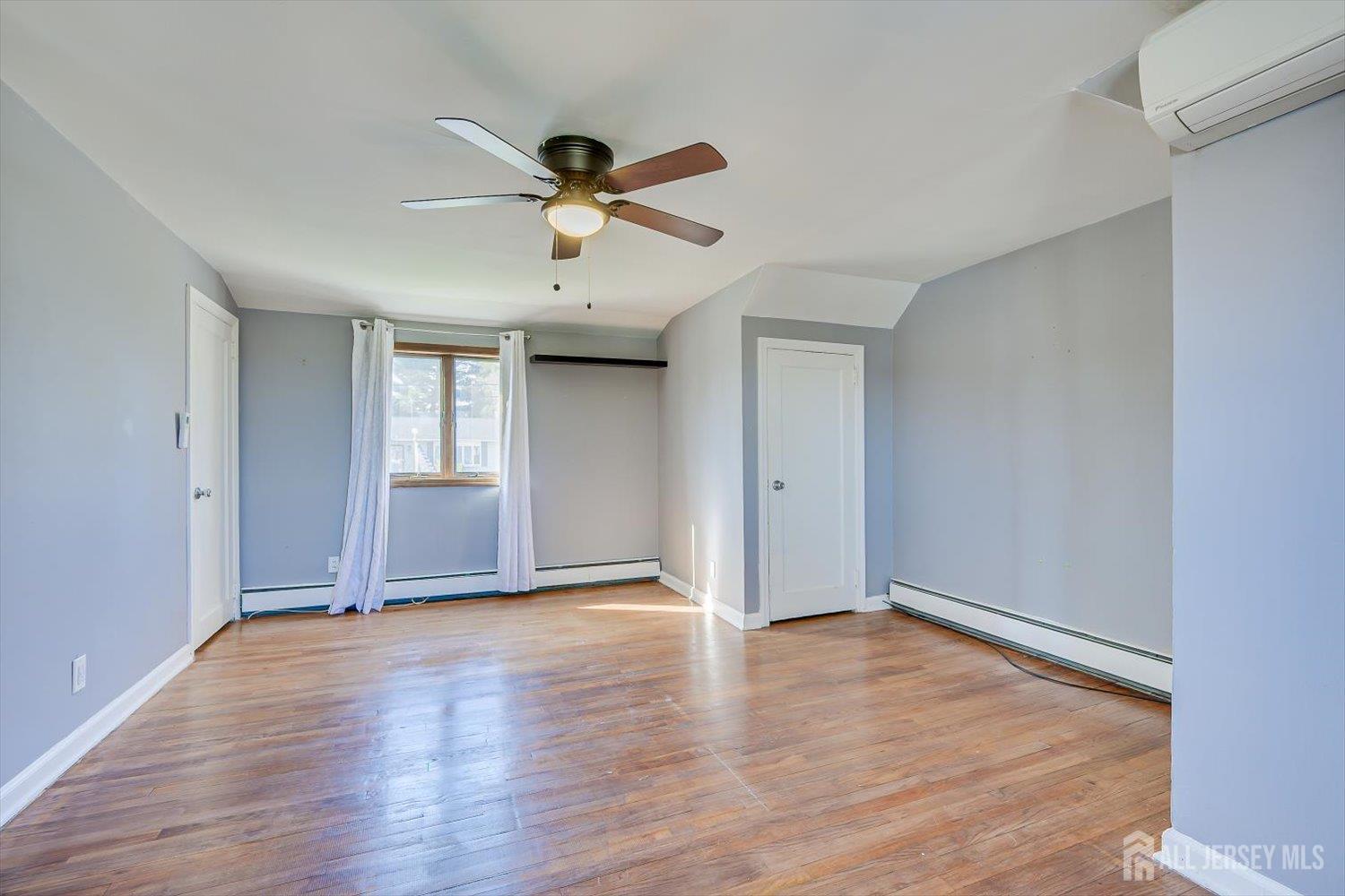 110 Normandy Road Colonia, NJ 07067 - Photo 37 of 57 an empty room with wooden floor chandelier fan and windows