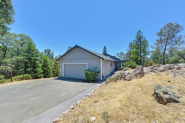 a view of a house with a dirt yard and a large tree
