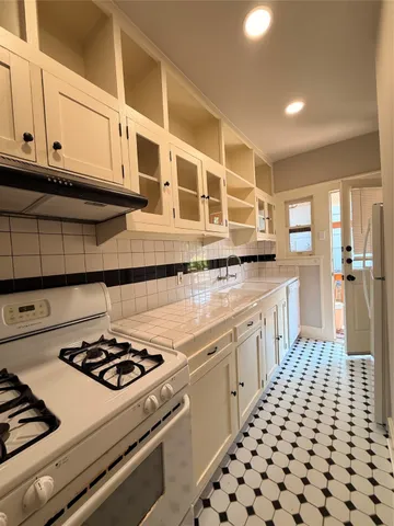 a kitchen with a stove and white cabinets
