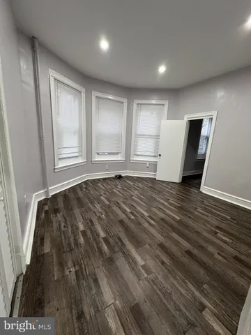 a view of an empty room with wooden floor and window
