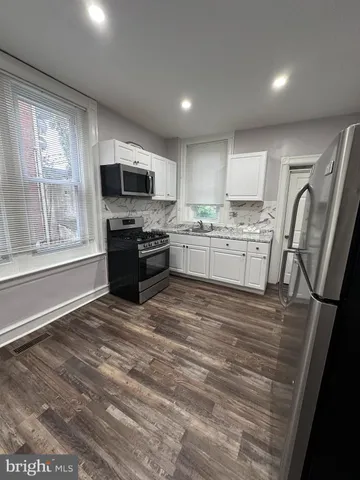 a kitchen with stainless steel appliances granite countertop a stove top oven a sink dishwasher a refrigerator and a fireplace with wooden floor