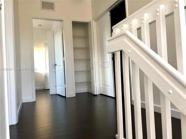 a view of a hallway with wooden floor and stairs