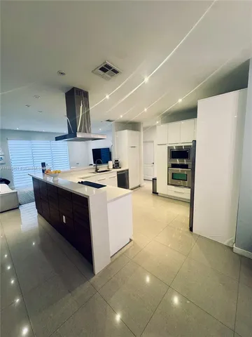 a large kitchen with stainless steel appliances a sink a stove a refrigerator and cabinets