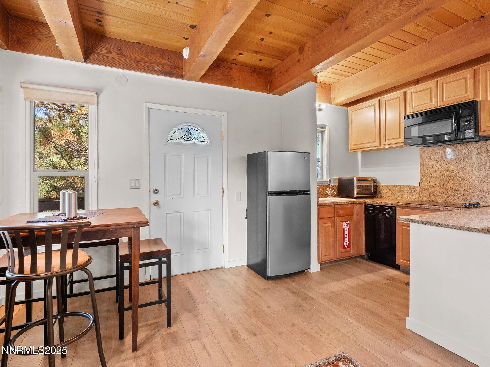 259 Tramway Drive, Unit 3 Stateline, NV 89449 - Photo 14 of 29 a kitchen with a refrigerator a microwave oven on a dining table and chairs with wooden floor