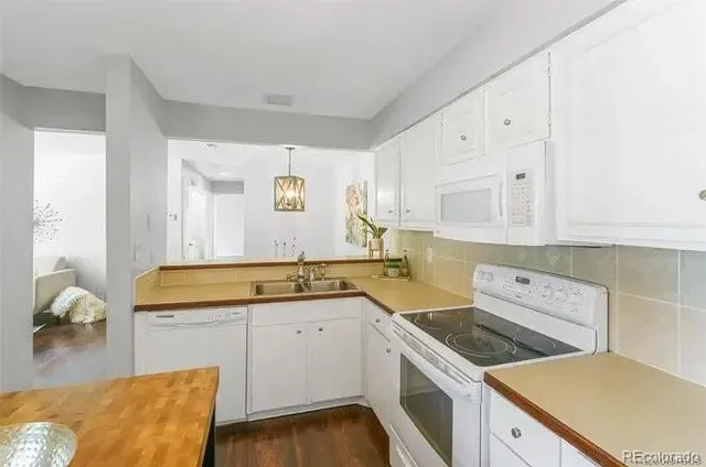 a kitchen with a sink dishwasher stove and white cabinets