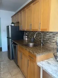 a kitchen with granite countertop a sink a stove and refrigerator